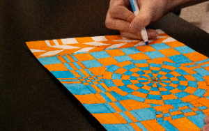  A student colors in an orange and blue geometric design